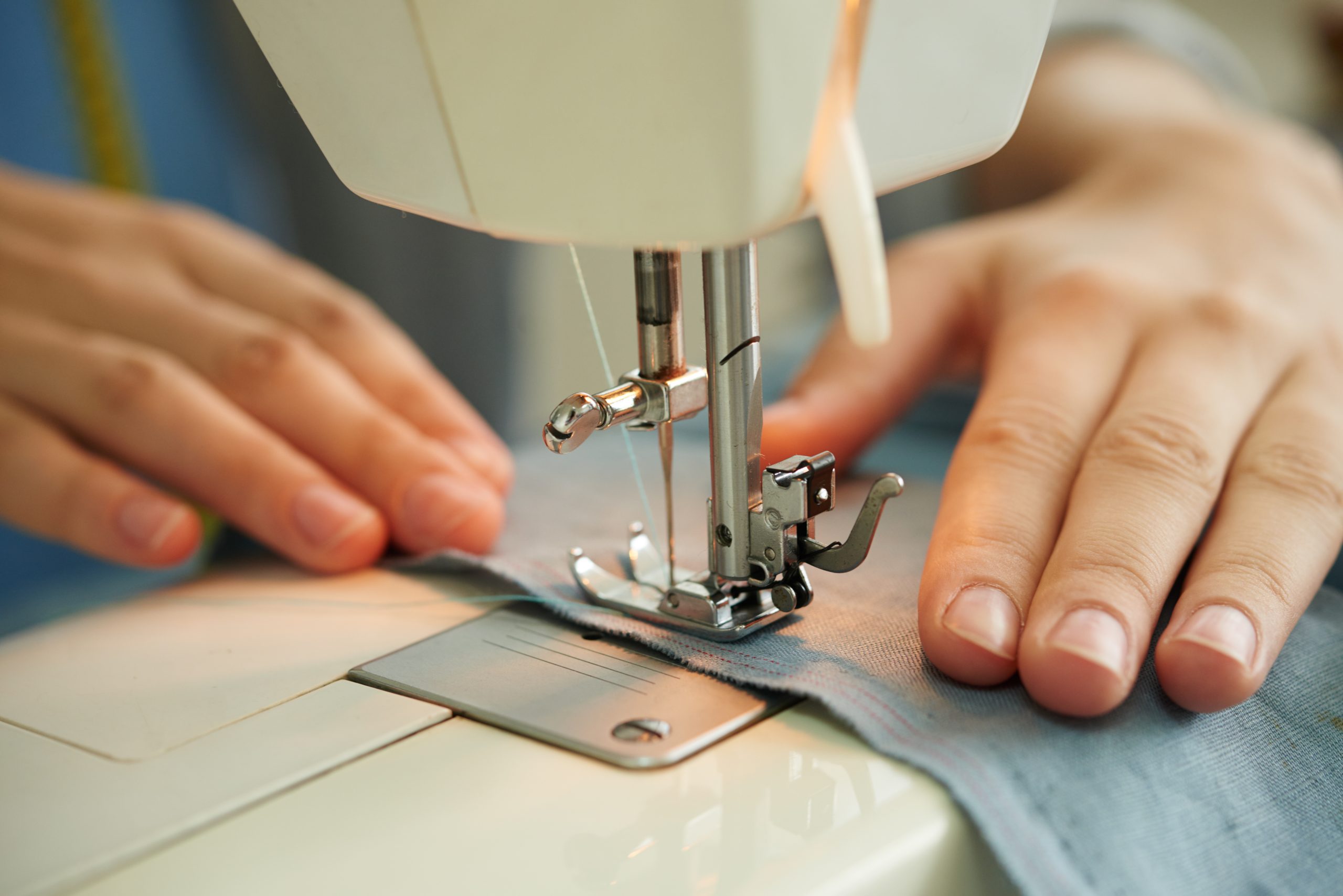 Hands of female tailor using sewing machine at work